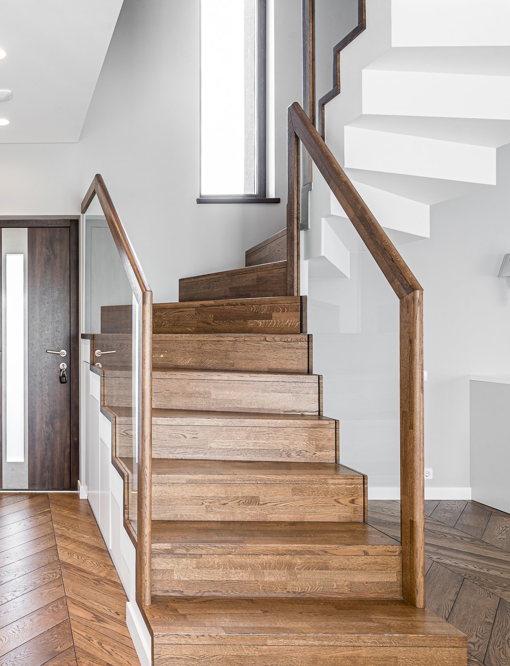 Neįpareigojanti klasika: subtilus Chevron parketo, ąžuolinių laiptų ir vidaus durų derinys