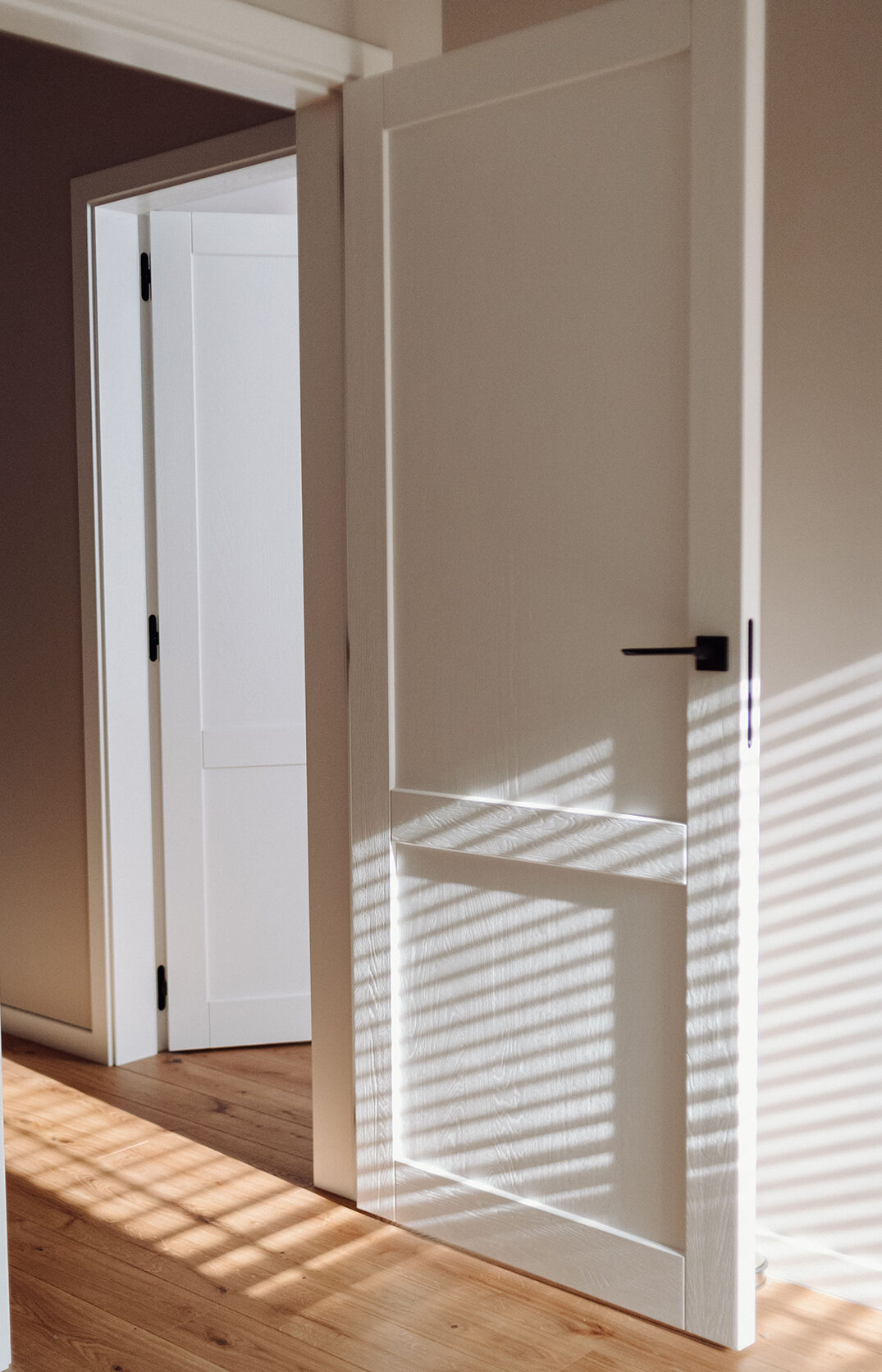 Subalansuotas interjeras: grindys, durys, net turėklai laiptais sumaniai suderinti tarpusavyje